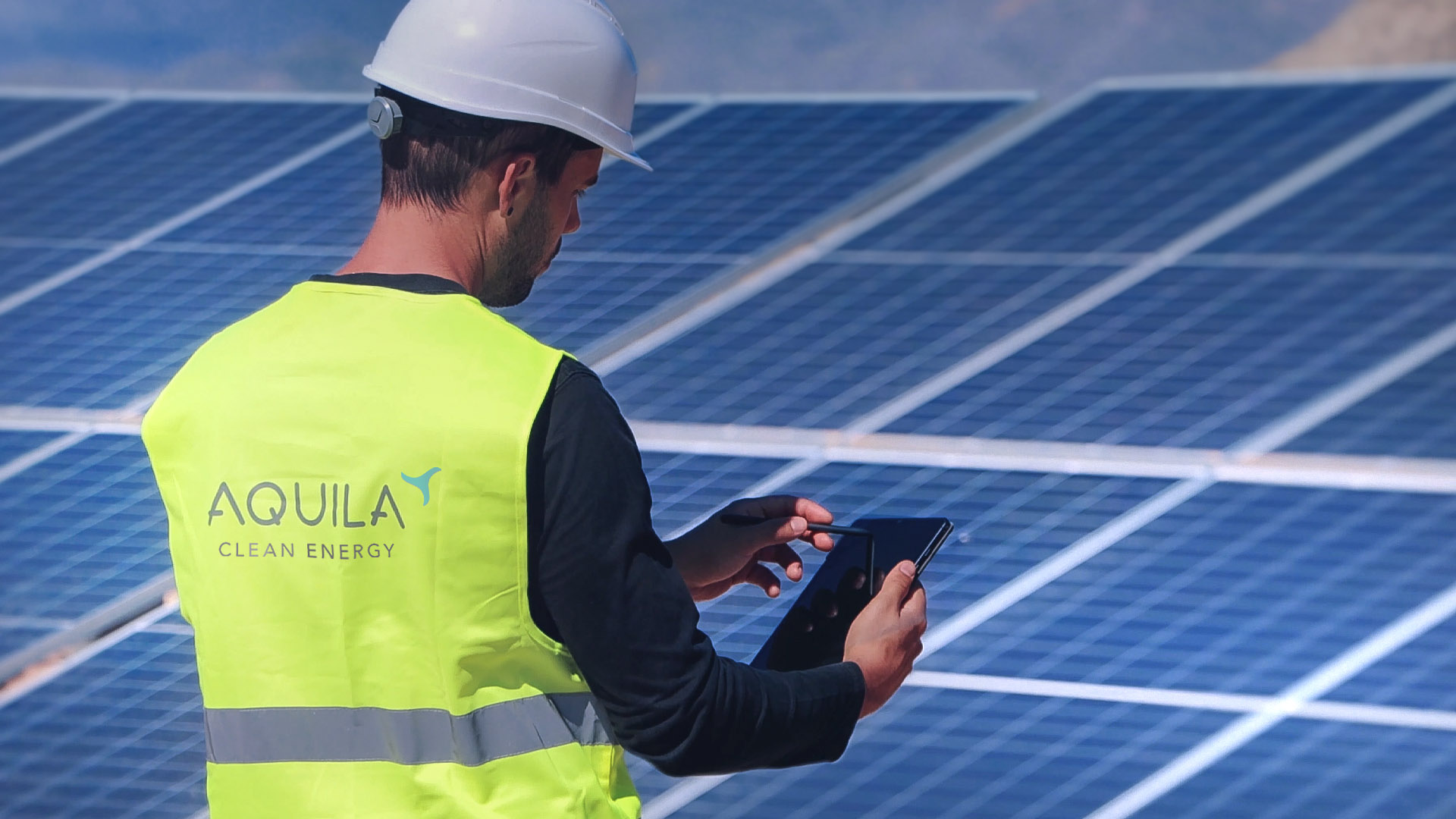 Un dipendente di Aquila Clean Energy davanti a un pannello solare fotovoltaico